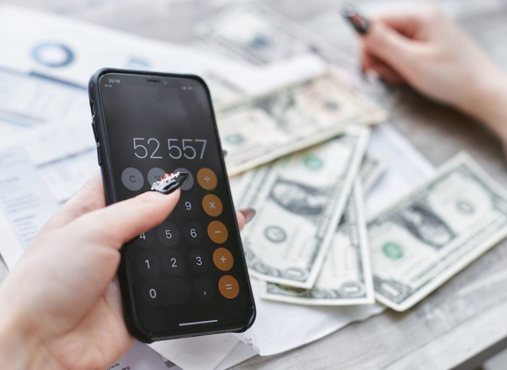 Hands holding a smartphone next to cash when planning the cost of mobile app development