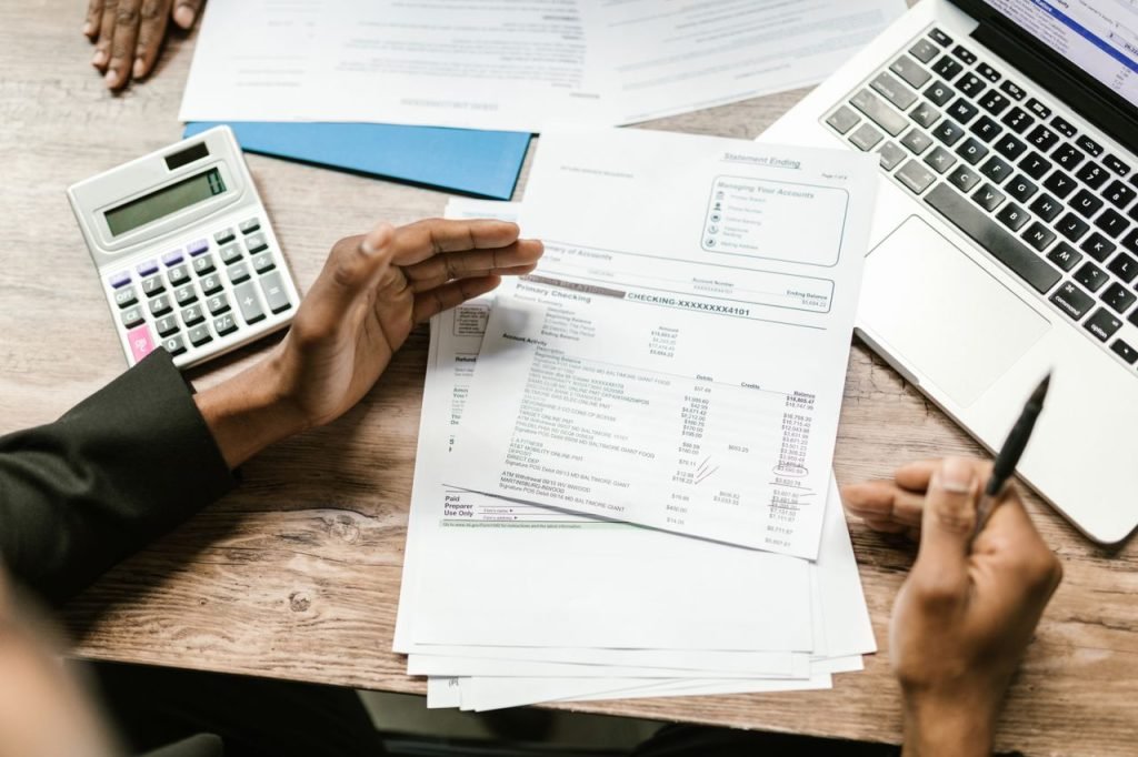 Financial documents, calculator and laptop for automating bookkeeping, reporting and cash flow