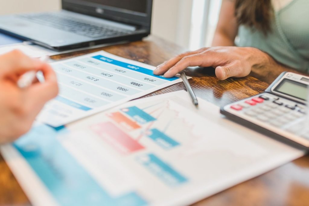 Graphs, a laptop and a calculator on a desk while planning a SaaS product and its pricing